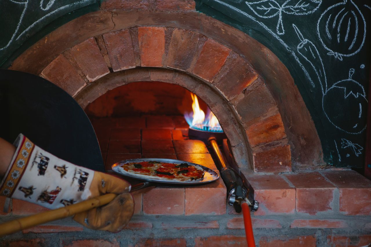 A delicious pizza baking in a traditional wood-fired brick oven in a cozy Italian pizzeria.